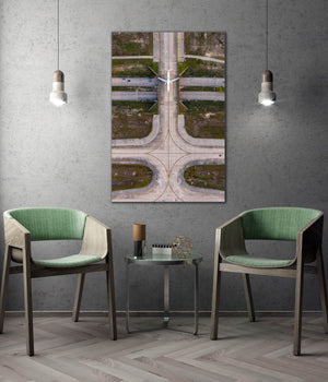 a modern living room with a large wall-mounted clock, two green armchairs, and a small table with a glass top.