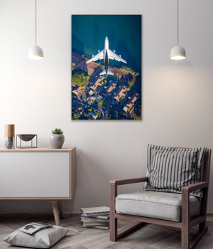 a large aerial view of a plane flying over a city, with a building and trees visible below.