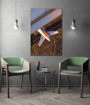 a large framed picture of an airplane on the wall, with two green chairs positioned in front of it.