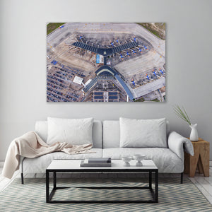 a large wall-mounted painting depicting an aerial view of an airport terminal with multiple airplanes parked at the gates.