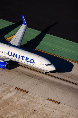 An aerial view of a United Airlines jet parked on the tarmac at an airport.