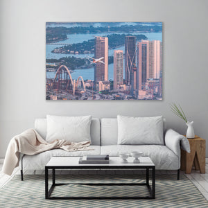 a large cityscape with tall buildings, a bridge, and a plane flying over the city.