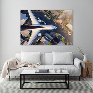 a large aerial view of a city with a white airplane flying over it, and a cozy living room with a white sofa and a coffee table below.