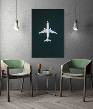 a modern living room with a large abstract painting of a white airplane on a dark background hanging on the wall. The room is furnished with two green chairs, and there is a small table between them. The overall design and decor create a contemporary and stylish atmosphere.