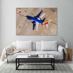 a large airplane parked on a tarmac, with a white sofa and a coffee table in the foreground.