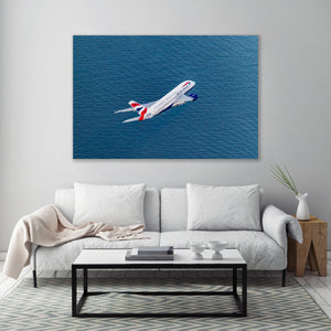 a large airplane flying over a body of water, with a white couch and a coffee table in the foreground.