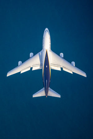 An aerial view of a large commercial airplane flying over a body of water.