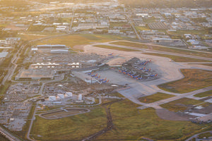 An aerial view of an airport with multiple airplanes parked on the tarmac, surrounded by buildings and other airport infrastructure.
