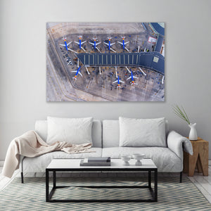 a large wall-mounted painting depicting an aerial view of an airport tarmac with multiple airplanes parked in rows.