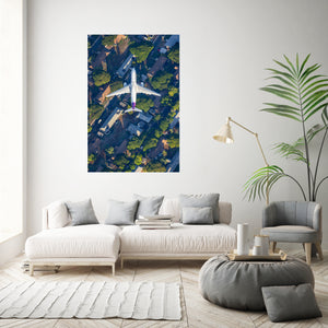 a modern living room with a large white sofa, a round coffee table, and a potted plant. A large poster of an aerial view of a city is displayed on the wall above the sofa.