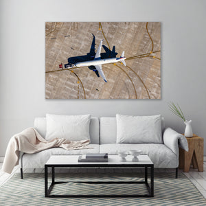 a large, white couch with a coffee table in front of it, set against a wall with a large, framed photograph of an airplane hanging above it.