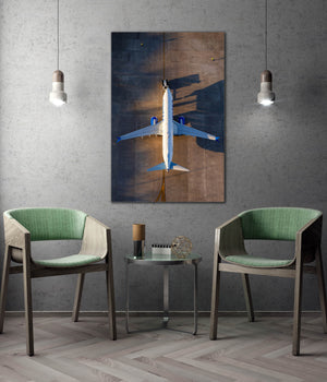 a modern living room with a large framed photograph of an airplane hanging on the wall, flanked by two green chairs.