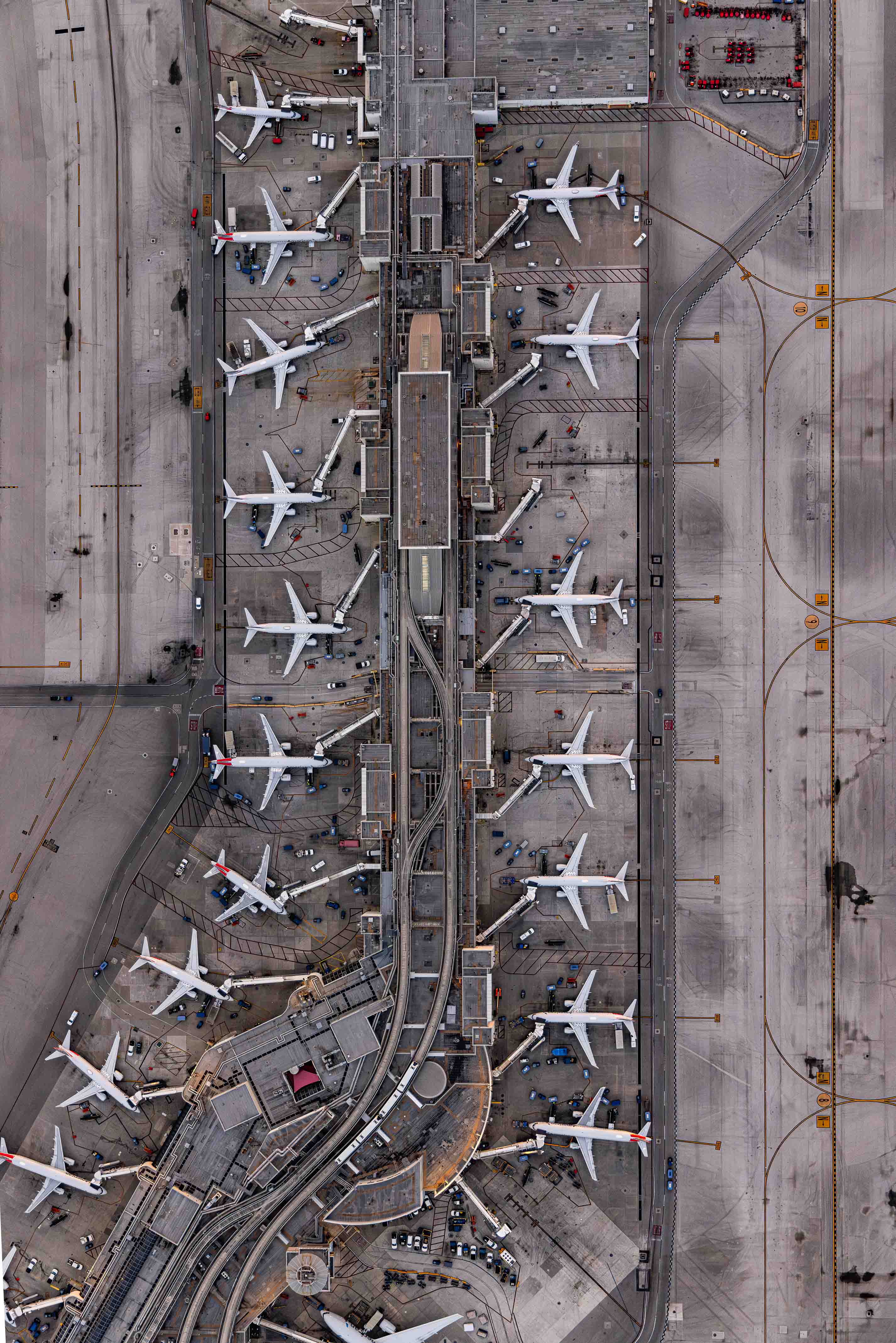 An aerial view of an airport with multiple rows of parked airplanes on the tarmac.