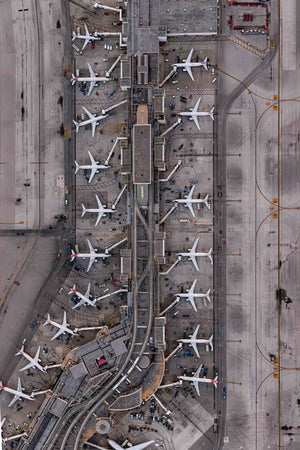 An aerial view of an airport with multiple rows of parked airplanes on the tarmac.