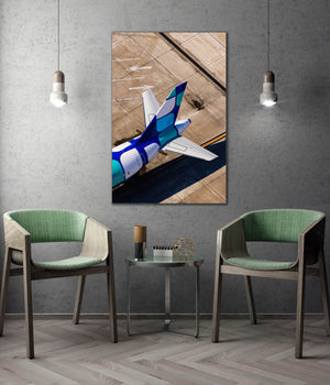 a modern interior design with a large wall-mounted photograph of a blue and white airplane on a wooden surface, flanked by two green chairs.