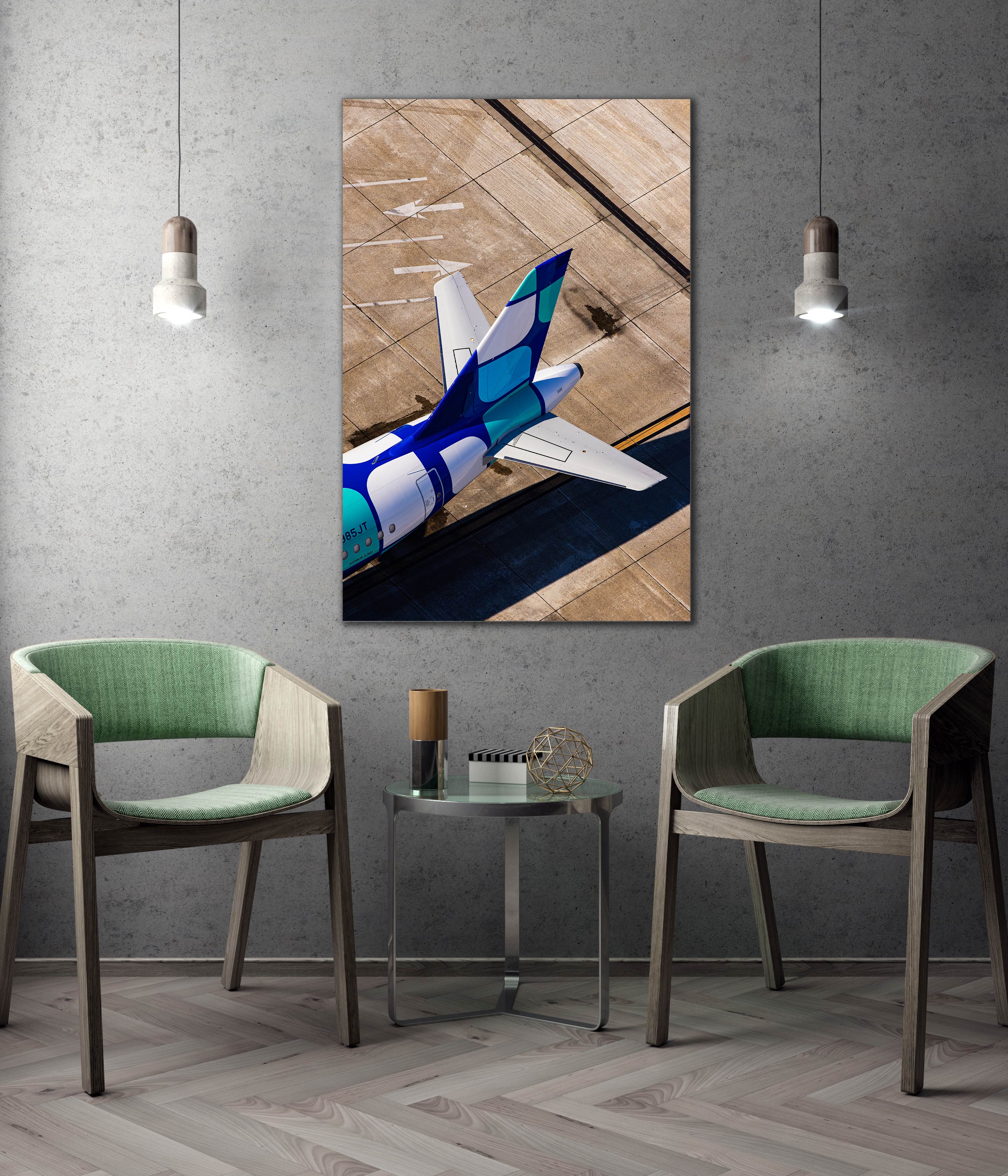 a modern interior design with a large wall-mounted photograph of a blue and white airplane on a wooden surface, flanked by two green chairs.