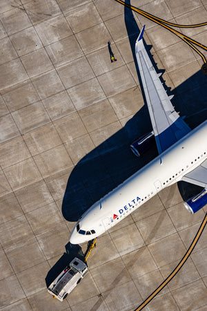 An aerial view of an airplane on the tarmac, with a ground support vehicle nearby.
