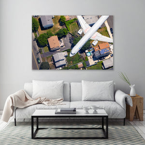 The image is an aerial view of a residential area with houses, trees, and a large airplane flying overhead.