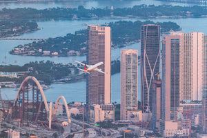 An aerial view of a city skyline with tall buildings, a river, and a ferris wheel in the foreground.