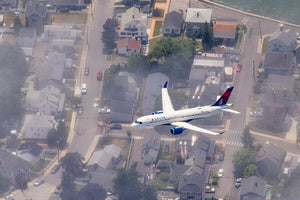 An aerial view of a residential neighborhood with a large commercial airplane flying overhead.