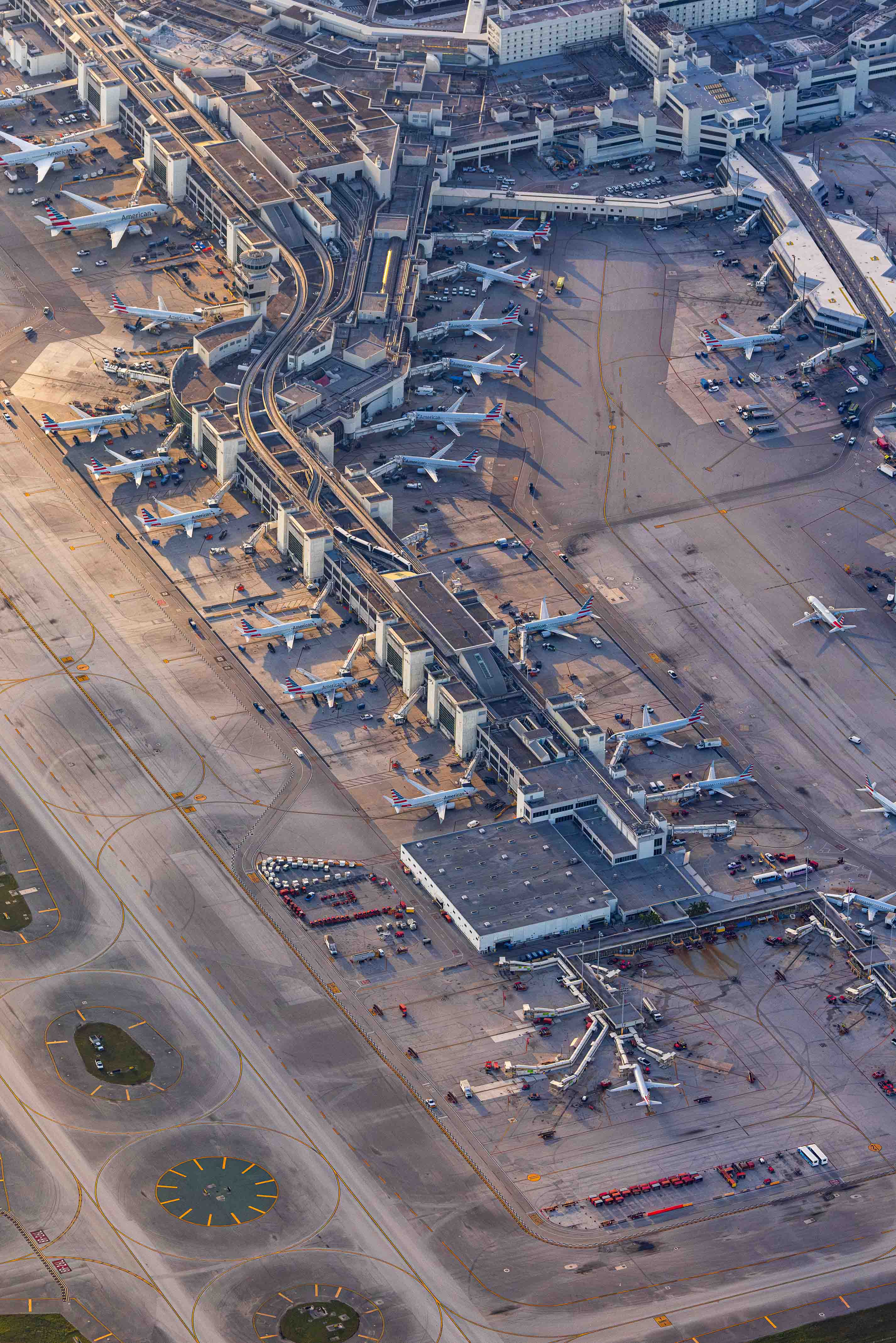 An aerial view of a busy airport with multiple runways, terminals, and airplanes parked or in motion.