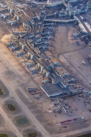 An aerial view of a busy airport with multiple runways, terminals, and airplanes parked or in motion.