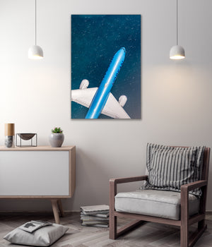 a modern living room with a minimalist design. The focal point is a large blue airplane painting hanging on the wall, which appears to be a representation of an airplane flying through a starry sky. The room is furnished with a wooden chair, a white cabinet, and a stack of books. The overall atmosphere of the room is clean and contemporary, with a touch of nature represented by the potted plant and the starry sky painting.