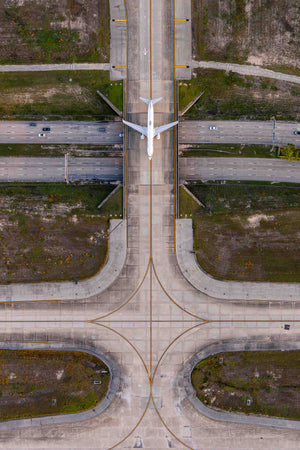 An aerial view of an airport runway with a large white airplane taking off or landing.