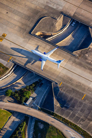 An aerial view of an airport runway with a large commercial airplane taking off.