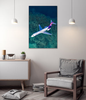 a large airplane flying over a blue ocean, with a minimalist living room setting below.