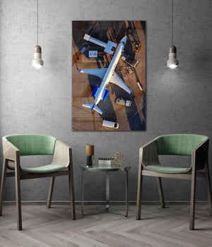 a large framed picture of an airplane on the wall, with two green chairs positioned in front of it.