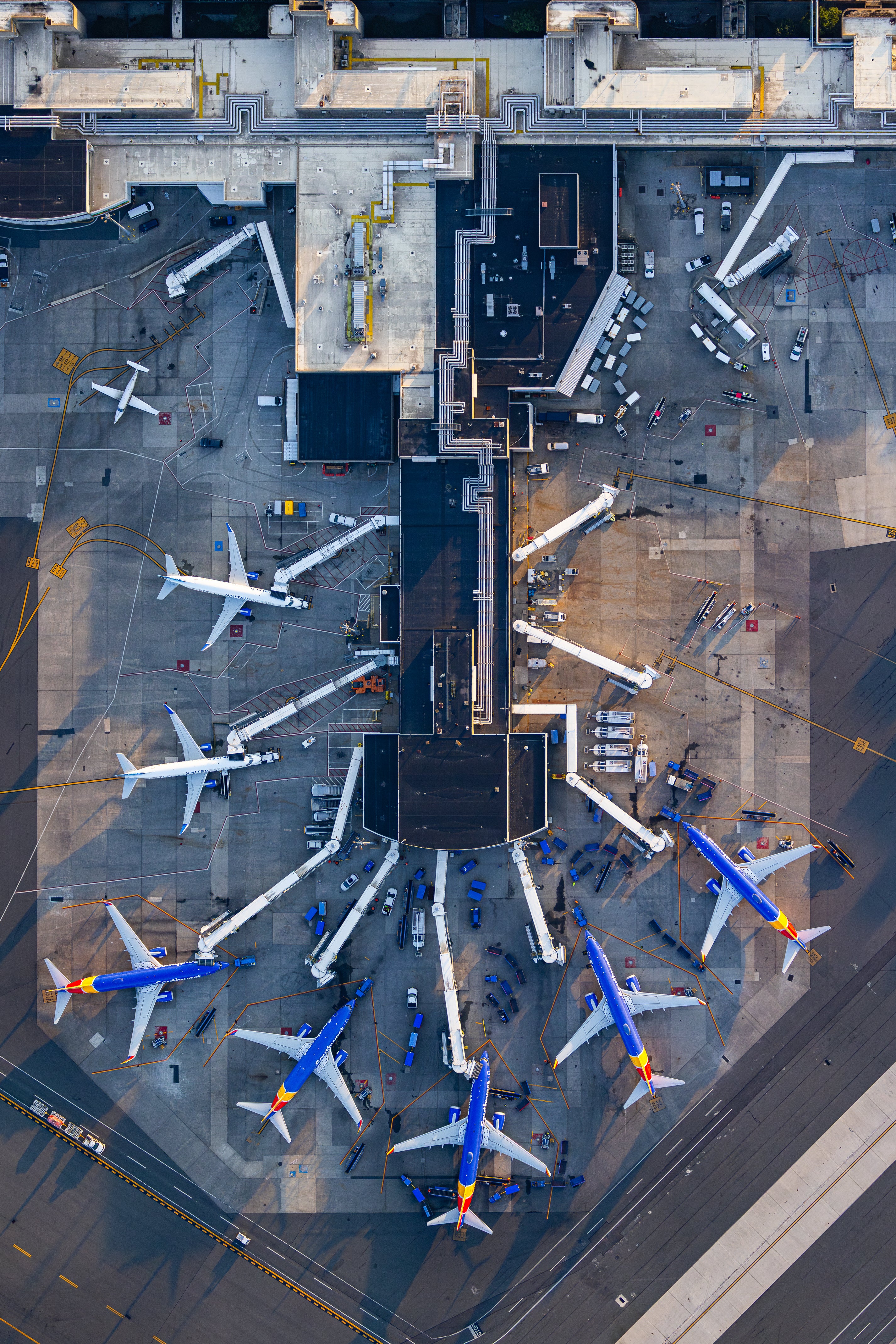 an airport tarmac with several airplanes parked and connected to the terminal building.