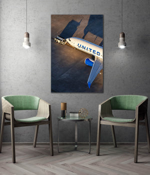 a large poster of a United Airlines airplane on the wall, with two green chairs positioned in front of it.