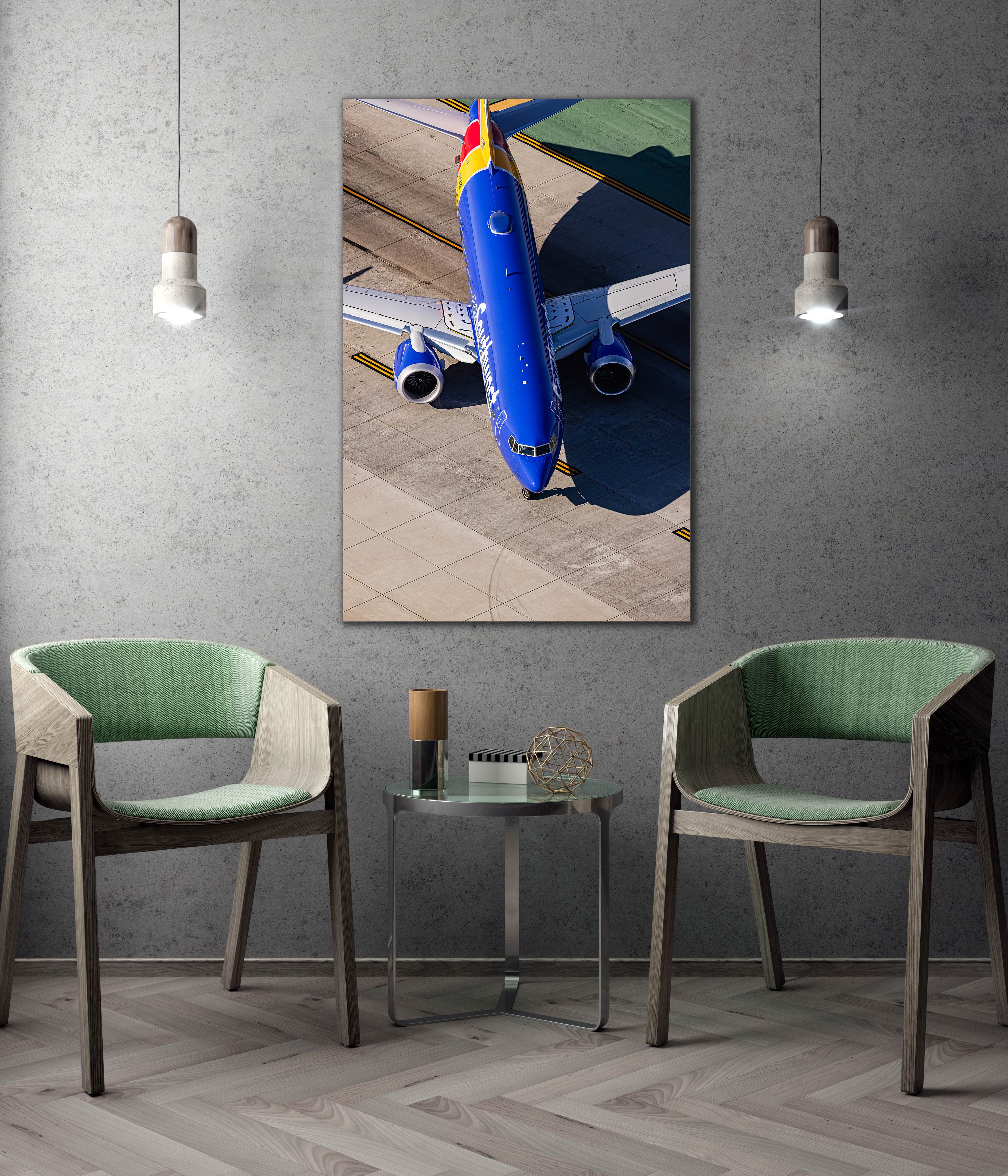 a large blue airplane on an airport tarmac, with two green chairs positioned in front of a small table.