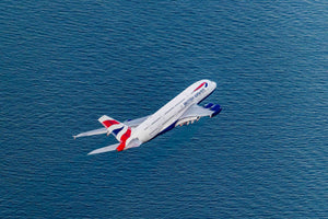 An aerial view of a British Airways airplane flying over a body of water.