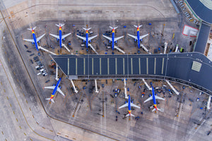 An aerial view of an airport with multiple airplanes parked at the terminal, including Southwest Airlines planes.