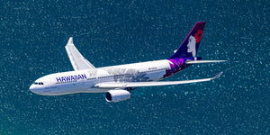 An aerial view of a Hawaiian Airlines passenger jet flying over a body of water.