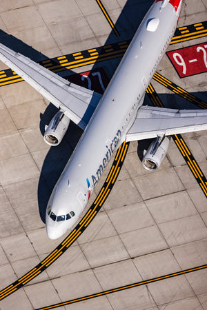 An American Airlines passenger jet is parked on the tarmac, with its landing gear down.