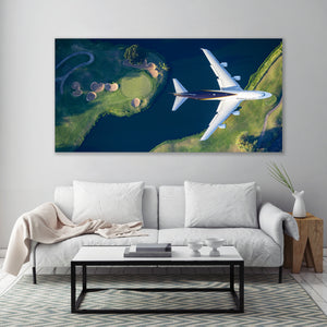 a large, white couch with a coffee table in front of it, set against a wall with a large, framed aerial photograph of a golf course and a plane flying over it.