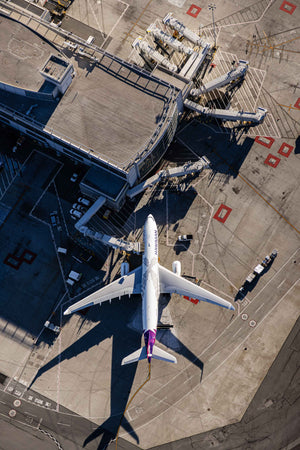 An aerial view of an airport tarmac with a large passenger jet parked at the terminal.