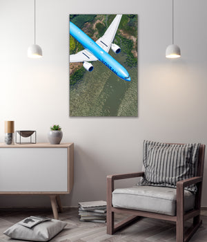 a large blue airplane flying over a green landscape, with a wooden chair and a bookshelf in the foreground.