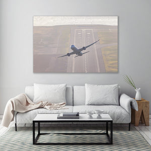 a large airplane taking off from an airport runway, with a white sofa and coffee table in the foreground.