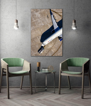 a modern interior design with a large framed photograph of an airplane hanging on the wall, flanked by two green chairs.