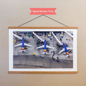 A framed photograph of several airplanes parked on an airport tarmac, with various ground support vehicles and equipment visible.
