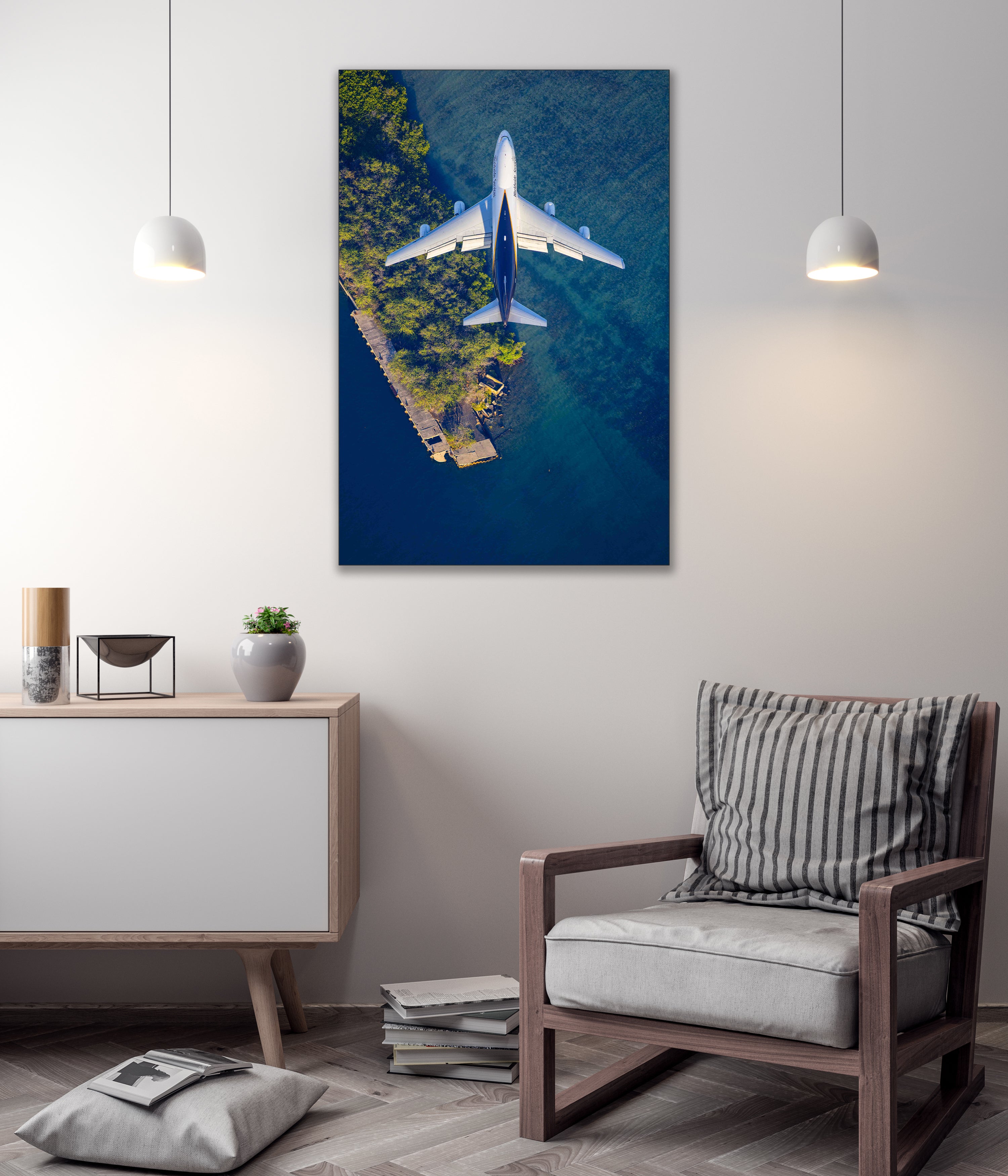 a large aerial view of a plane flying over a body of water, with a striped pillow on a chair in the foreground.