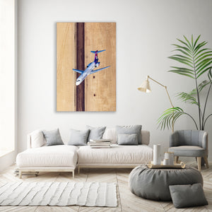 a modern living room with a large painting of a plane on the wall, a white sofa, a gray armchair, and a round coffee table with decorative items.