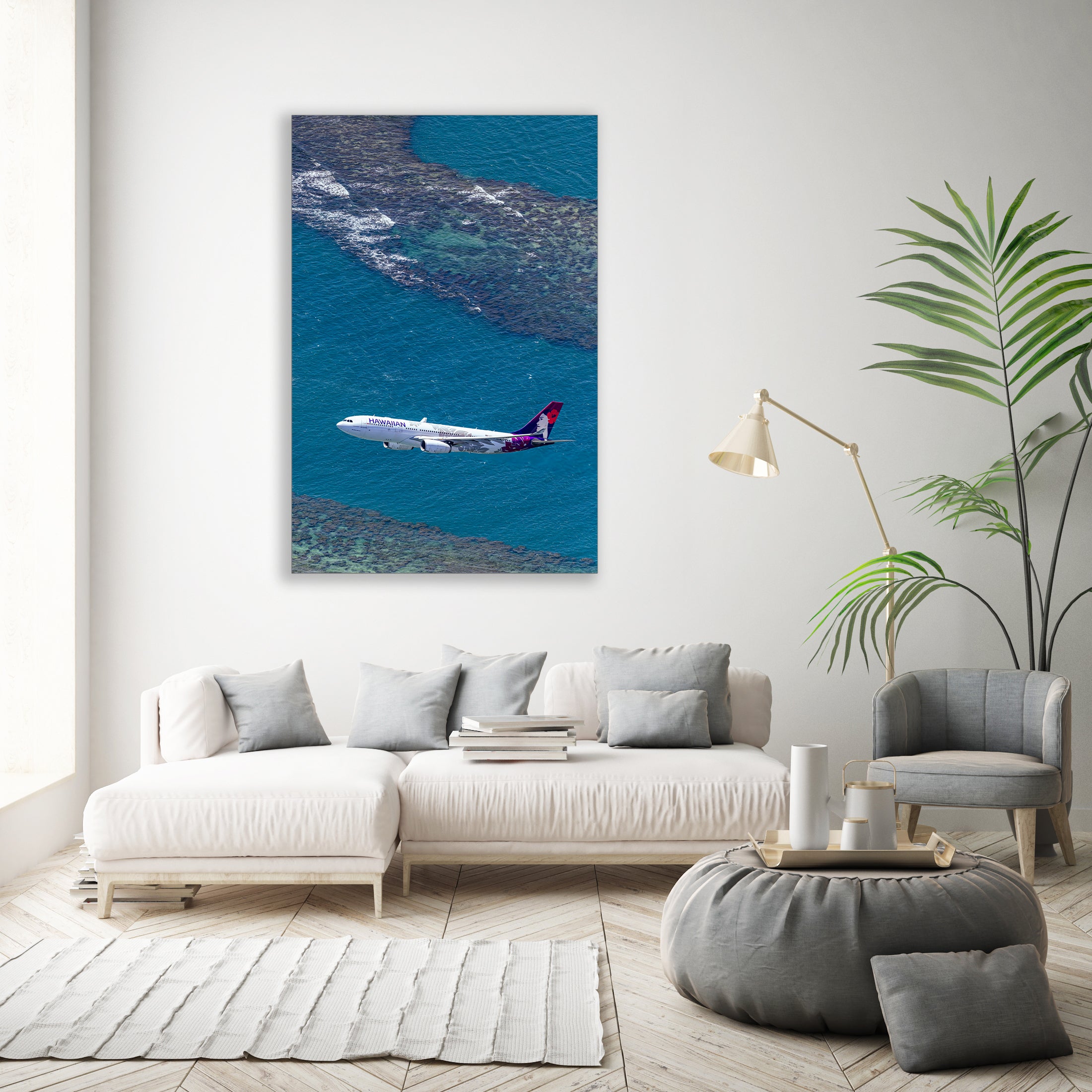 a large white sofa, a coffee table, a potted plant, and a painting of an airplane flying over a body of water.