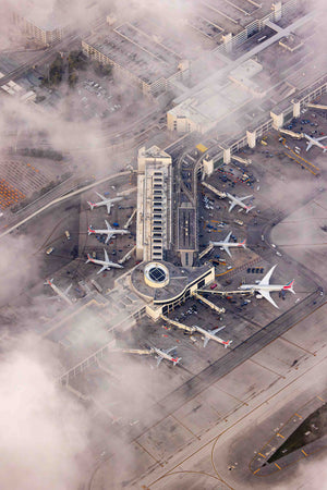 An aerial view of an airport with multiple airplanes parked at the terminals and a large building in the center.