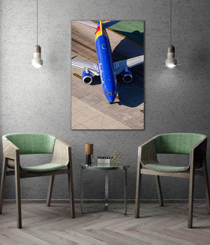 a large blue airplane on an airport tarmac, with two green chairs positioned in front of a small table.